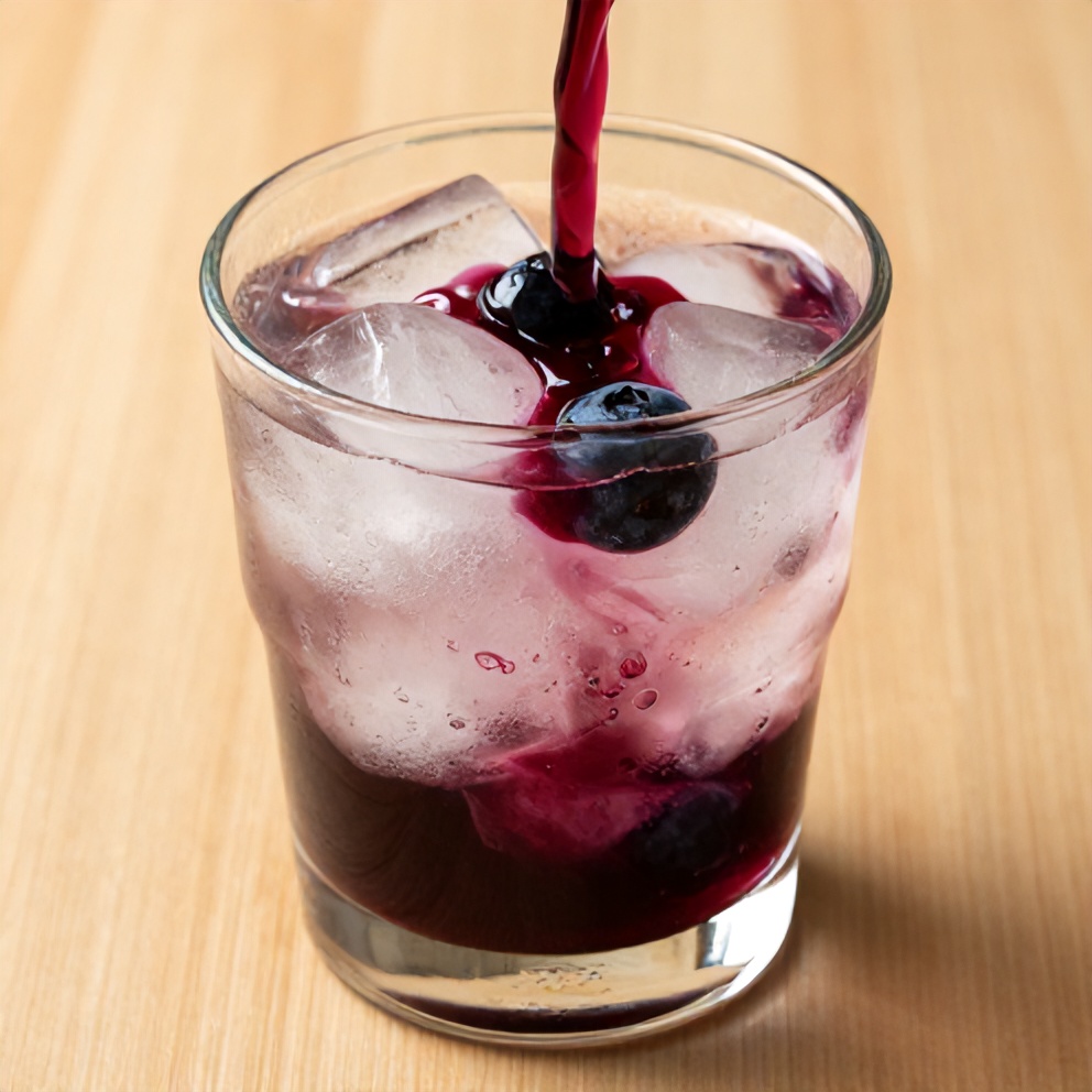 Blueberry syrup poured over ice in a glass