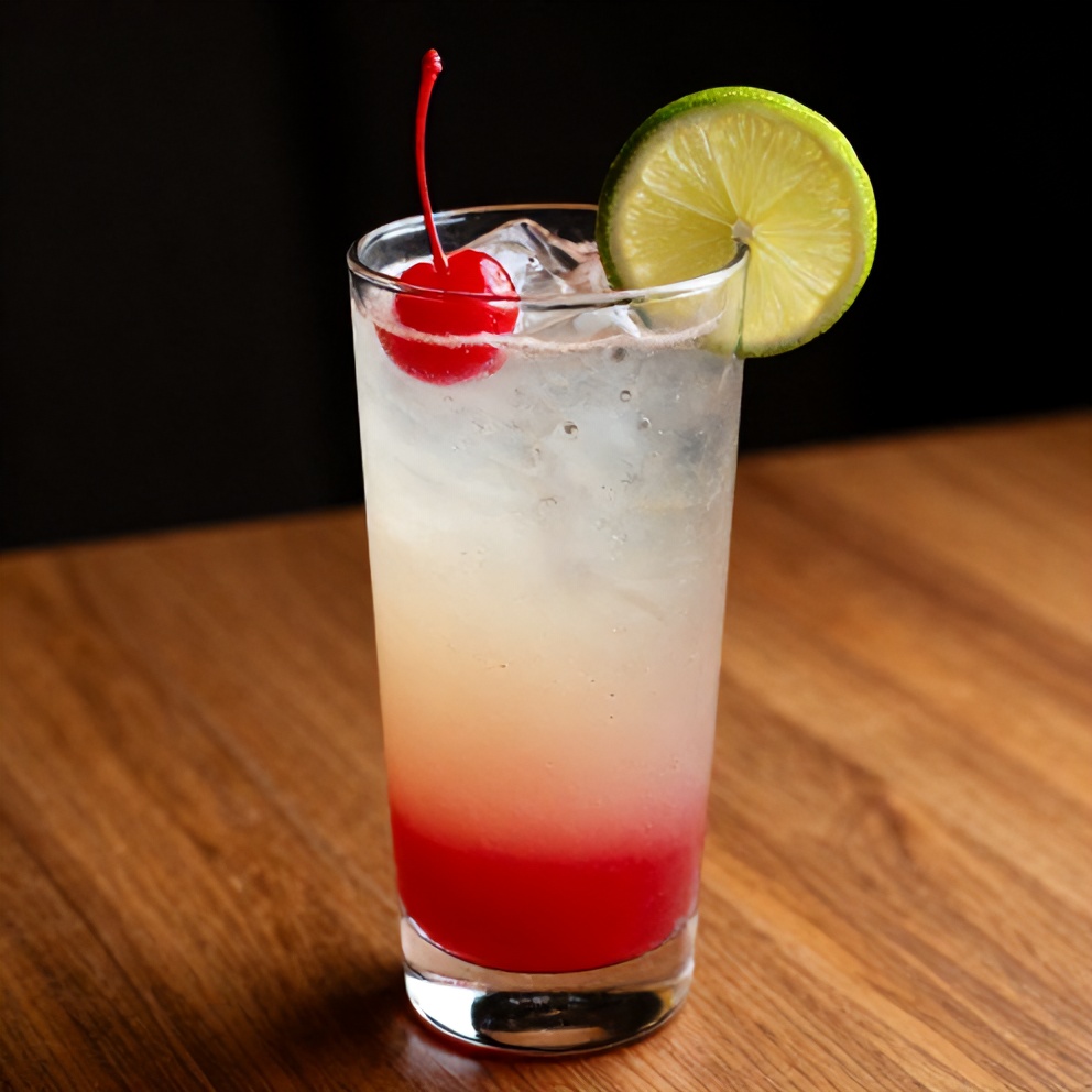 A glass of cherry limeade with a cherry and lime garnish, served on a wooden table