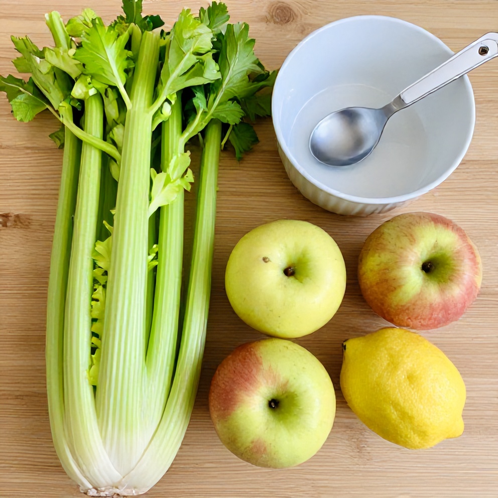 Raw celery, apples, and lemon on a wooden surface